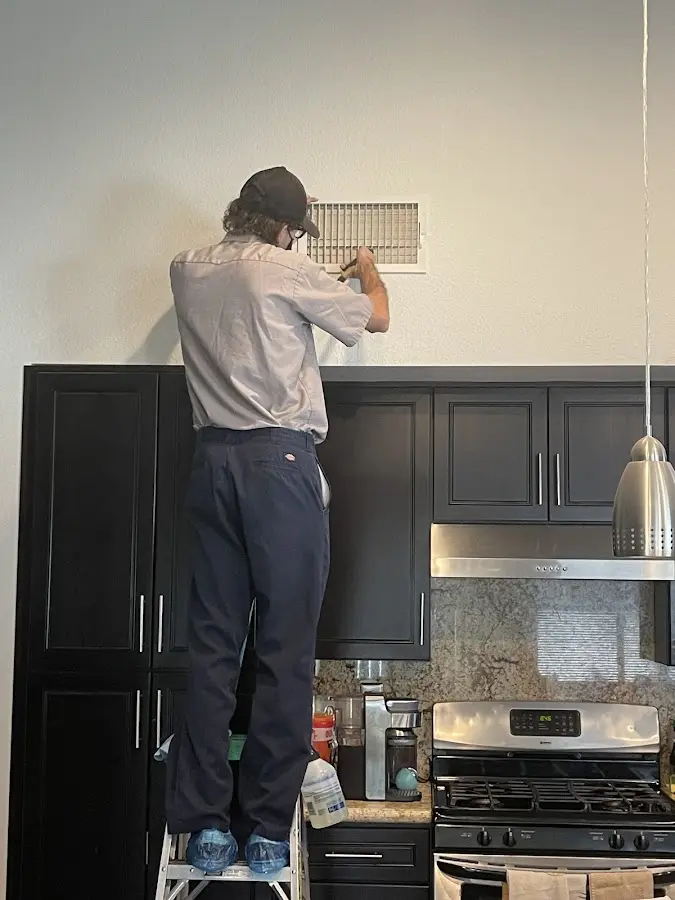 Technician inspecting an air vent during HVAC service in San Gabriel